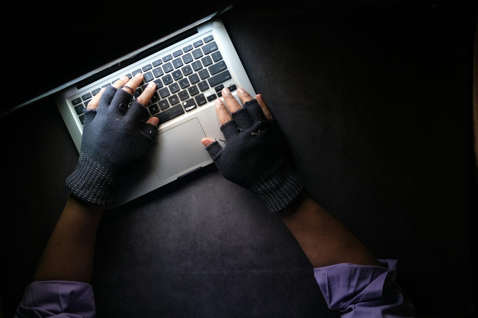 Person using a laptop in a dark setting representing digital technology and cyber investigations