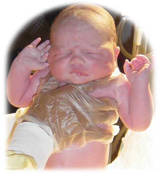 Newborn baby held by a gloved healthcare worker in a hospital