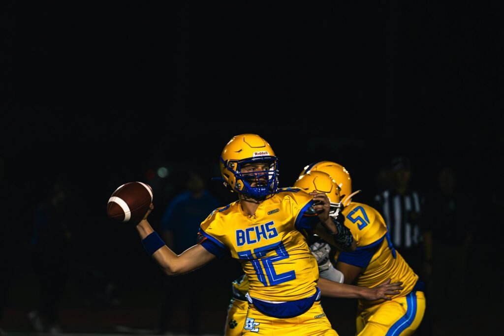Quarterback throwing a football during a night game